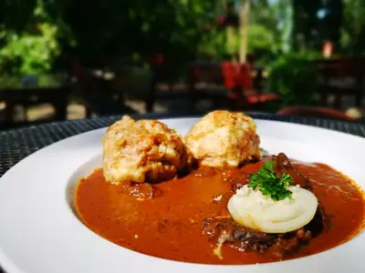 a white plate of food with meat and sauce at Hotel Ludmila in Mělník