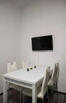 a white table and chairs with a television on a wall at Modern Apartment in the Center of Prague in Prague