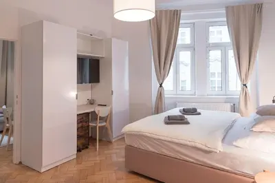 a white bedroom with a bed and a desk at Skolska Junior apartment in Prague