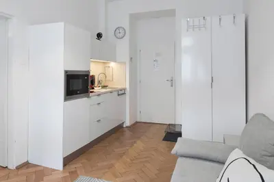 a living room with white cabinets and a kitchen at Skolska Junior apartment in Prague