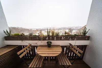a balcony with a wooden table and two benches at Malý byt s balkonem & free parking in Prague