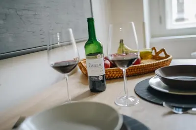two glasses of wine on a table with a basket of fruit at Cozy & comfortable apt walking anywhere you want SEN in Prague
