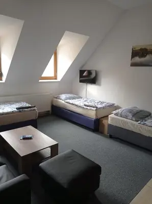 a attic room with two beds and a table at Penzion Pralinka in Rakovník
