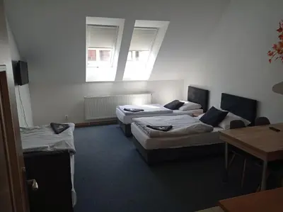 a room with three beds and a table and a window at Penzion Pralinka in Rakovník