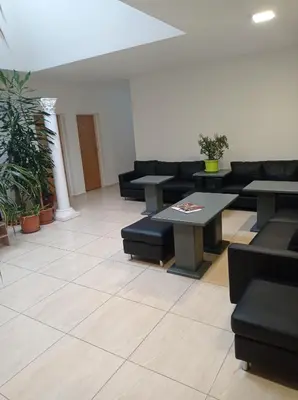 a waiting room with couches and tables and plants at Penzion Pralinka in Rakovník