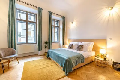 a bedroom with a bed and a chair and windows at Primavera - Castle view apartments in Prague