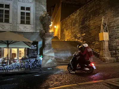 two people riding a motorcycle on a street at night at Primavera - Castle view apartments in Prague