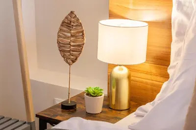 a lamp and a plant on a table next to a bed at Primavera - Castle view apartments in Prague