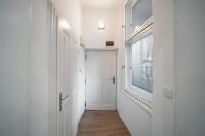a hallway with a white door and a window at Josefov Riverside Apartment in Prague