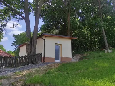 a small house with a fence and trees at Apartmán Višňová in Milovice