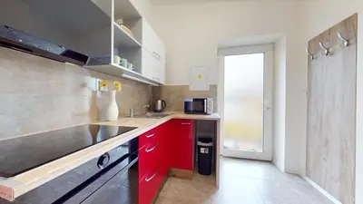 a small kitchen with red cabinets and a microwave at Apartmán Višňová in Milovice