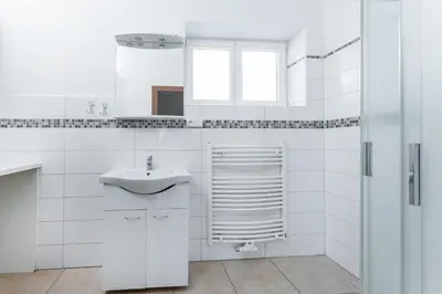 a white bathroom with a sink and a window at Apartmán Riegrovo náměstí in Poděbrady