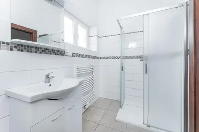 a white bathroom with a sink and a shower at Apartmán Riegrovo náměstí in Poděbrady