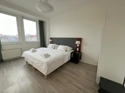 a bedroom with a bed with white sheets and two windows at Holiday home Prague in Prague