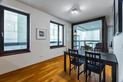 a dining room with a table and chairs and windows at Modern spacious flat with a terrace and a parking in Prague