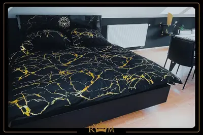 a bed with a black comforter with gold designs on it at RM Luxury Apartment in Prague • 6 People • Free Parking • Pets in Prague