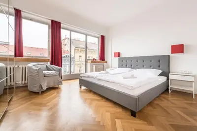 a bedroom with a bed and a chair and windows at Merkur apartments in Prague
