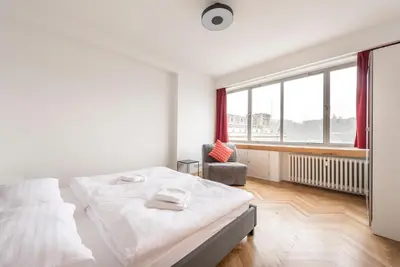 a white bedroom with a bed and a chair at Merkur apartments in Prague
