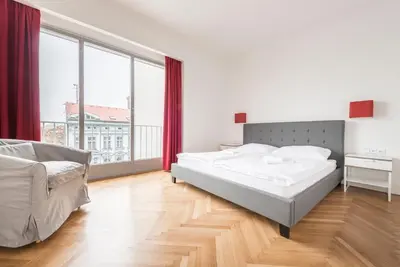 a bedroom with a bed and a large window at Merkur apartments in Prague