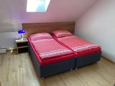 a bedroom with a bed with red sheets and pillows at Hrusická restaurace a penzion in Hrusice