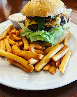a white plate with a hamburger and french fries at Hrusická restaurace a penzion in Hrusice