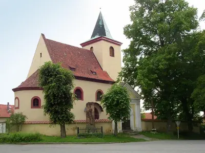 a large church with a steeple on top of it at Hrusická restaurace a penzion in Hrusice