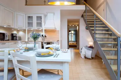 a kitchen and dining room with a white table and a staircase at Modern Apartment Charvatova in Prague