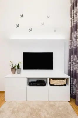 a living room with a white entertainment center with a television at Modern Apartment Charvatova in Prague