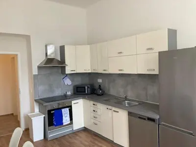 a kitchen with white cabinets and a sink and a refrigerator at Erbenova Apartments in Prague