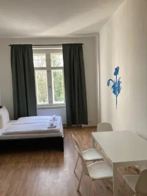 a bedroom with a bed and a table and a window at Erbenova Apartments in Prague
