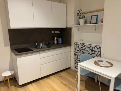 a small kitchen with white cabinets and a table at Flat white flat in Prague