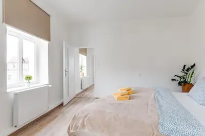 a white bedroom with a bed and a window at Modern, bright and spacious apartment in Prague