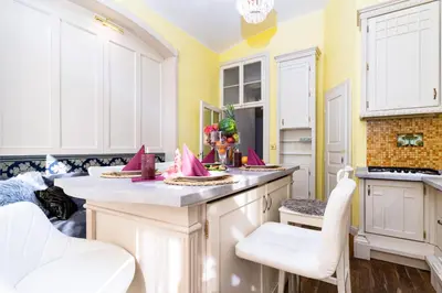 a kitchen with a counter with white cabinets and white chairs at Imperial Deluxe Suite in Prague