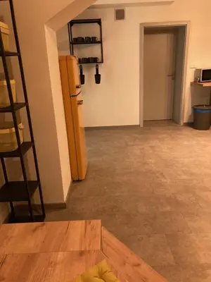 an empty room with a kitchen and a room with a table at Capsule hostel Erbenova in Prague