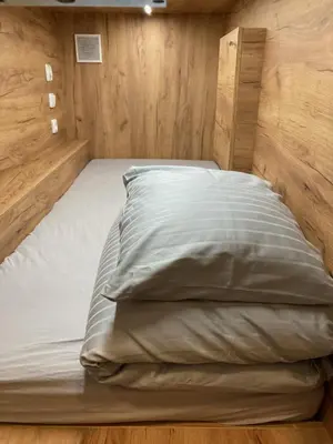 a large bed in a room with wooden walls at Capsule hostel Erbenova in Prague