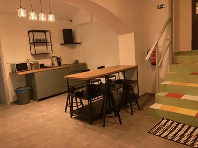 a room with a table and a kitchen and stairs at Capsule hostel Erbenova in Prague