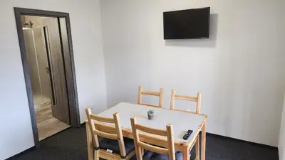 a dining room table with three chairs and a television at Penzion-Dubno in Dubno