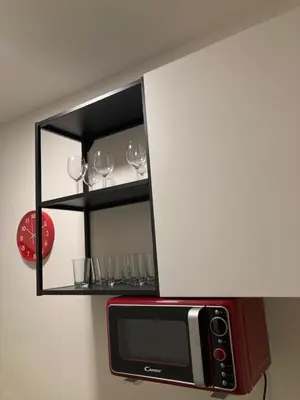 a shelf above a microwave with wine glasses on it at Capsule hostel Žižkov tower in Prague