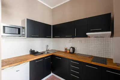 a kitchen with black cabinets and a microwave at Vals Garden Apartment in Prague