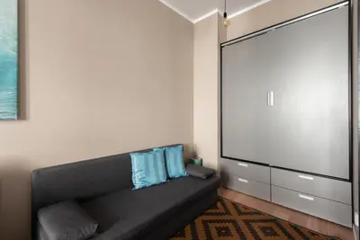 a living room with a black couch and a large screen at Vals Garden Apartment in Prague