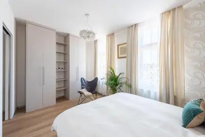 a white bedroom with a large bed and a chair at New modern apartment 5. floor in Prague