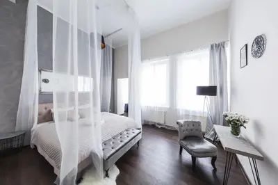 a white bedroom with a bed and a chair at Bohéme Apartments Old Town Square in Prague