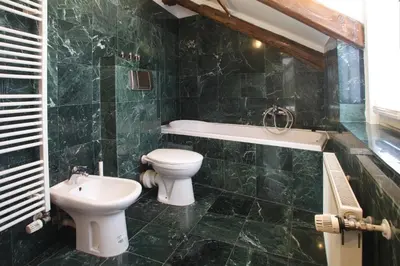 a green tiled bathroom with a toilet and a sink at Bohéme Apartments Old Town Square in Prague