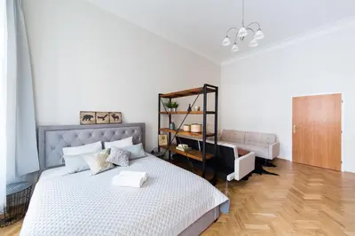a white bedroom with a bed and a mirror at Bohéme Apartments Old Town Square in Prague