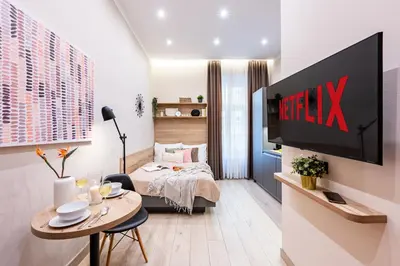 a living room with a bed and a tv on a wall at Prague Days - Modern Studios - 7 min Wenceslas Square in Prague