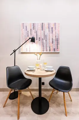 a table with two black chairs and a lamp at Prague Days - Modern Studios - 7 min Wenceslas Square in Prague
