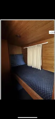 a small bed in a room with a curtain at Zouw Hausboat Zakotven -pouze ubytovaní in Roudnice nad Labem