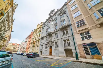 a large white building with cars parked on a street at New apartments near Dancing house in Prague