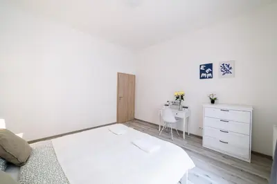 a white bedroom with a bed and a desk at New apartments near Dancing house in Prague