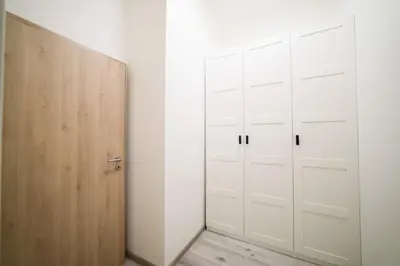 a closet with white cabinets and a wooden door at New apartments near Dancing house in Prague
